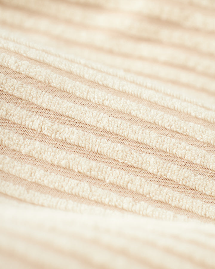 Close-up of The Tropez Jacquard Short - Scallop Stripe by Dandy Del Mar, featuring a beige textured fabric with evenly spaced horizontal ridges, reminiscent of jacquard striped terry.