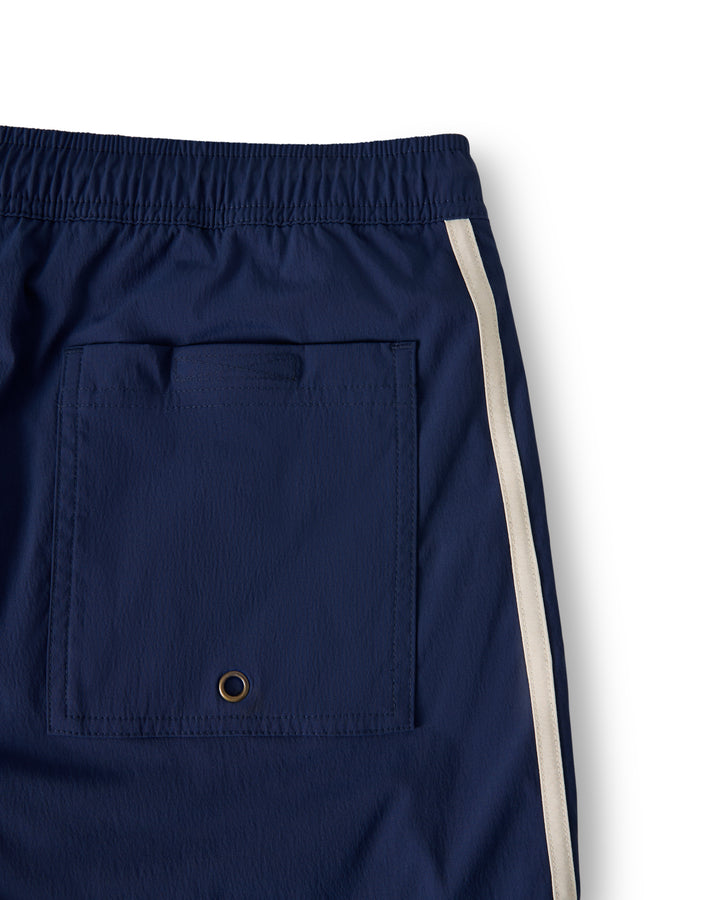 Close-up of The Ventura Volley Short - Anchor by Dandy Del Mar: blue swim shorts featuring an elastic waistband, back pocket with a grommet, white side stripe, and comfy micro mesh liner.