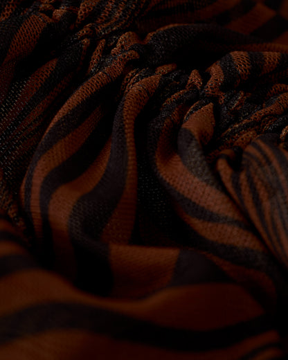 A close-up of the breathable mesh fabric from The Athena Skirt - Onyx by Dandy Del Mar, showcasing brown and black zebra stripes with ruching and a textured appearance, makes it perfect as a stylish beach coverup.